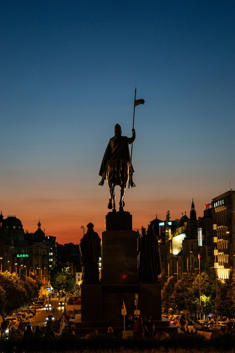 a statue of a man holding a flag in front of a city ISf