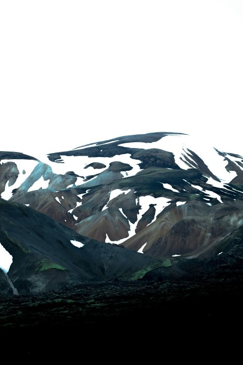 a snowy mountain with a body of water in the background