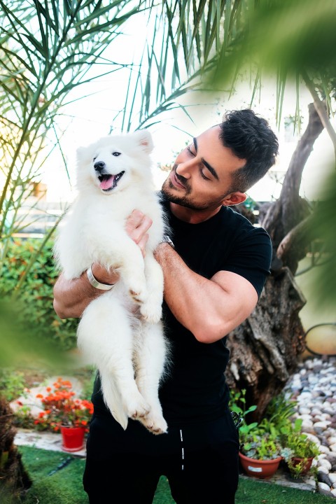 man in black crew neck t shirt holding white puppy