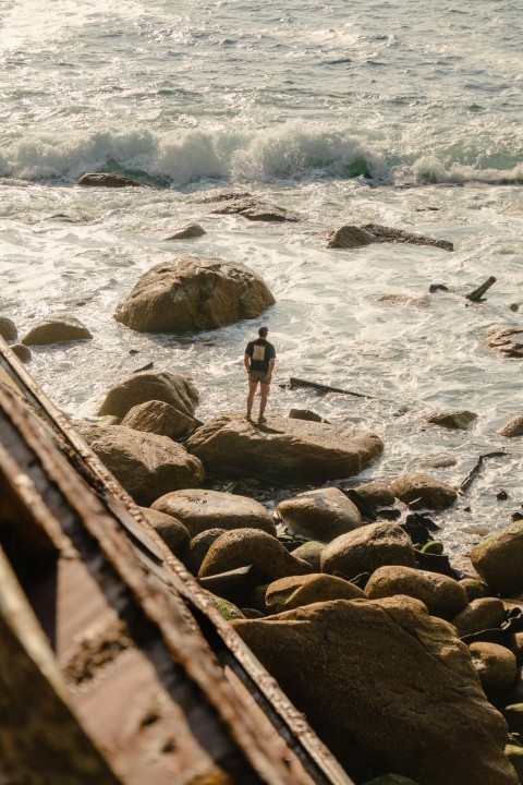 a person standing on rocks near the ocean