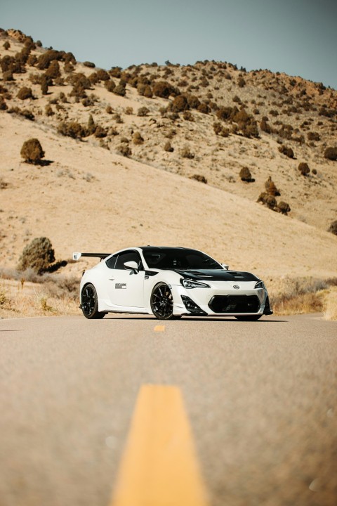 white and black porsche 911 on brown sand