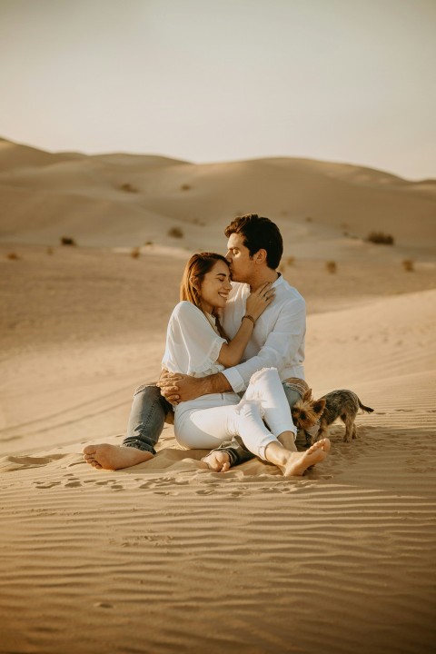 couple sitting on sand during daytime