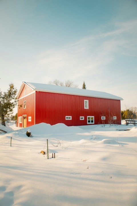 a red barn in the middle of a snowy field