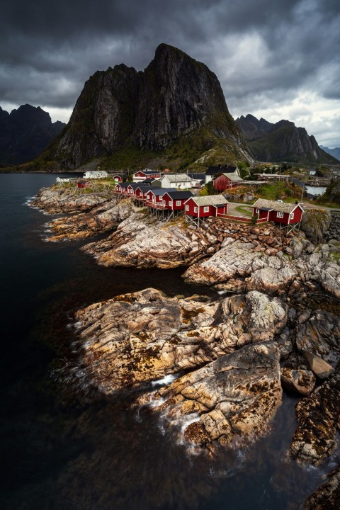 a red house sitting on top of a rocky shore