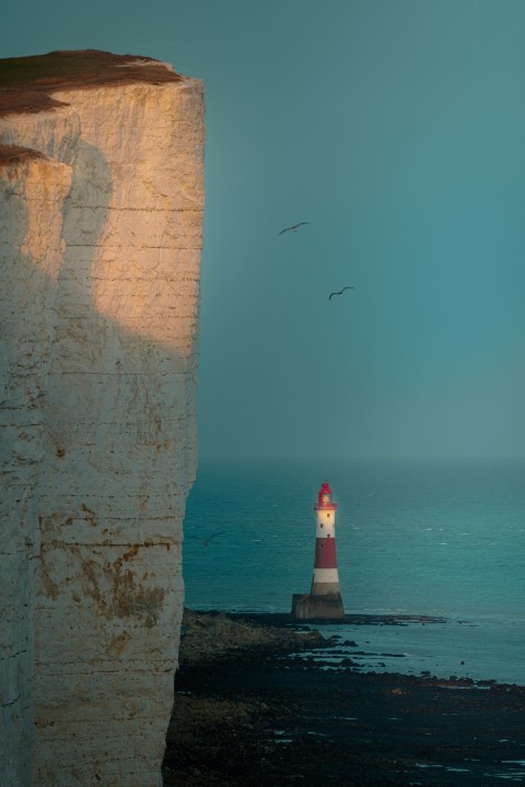 a red and white light house sitting on top of a cliff CDR3 b