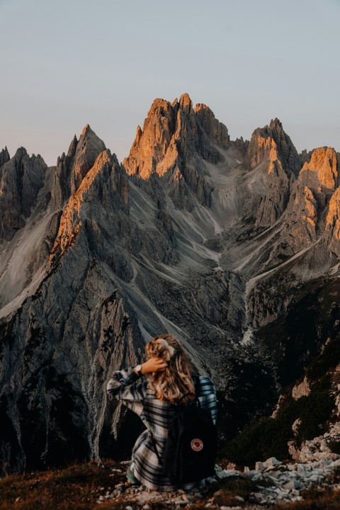 woman in black jacket taking photo of gray rocky mountain during daytime