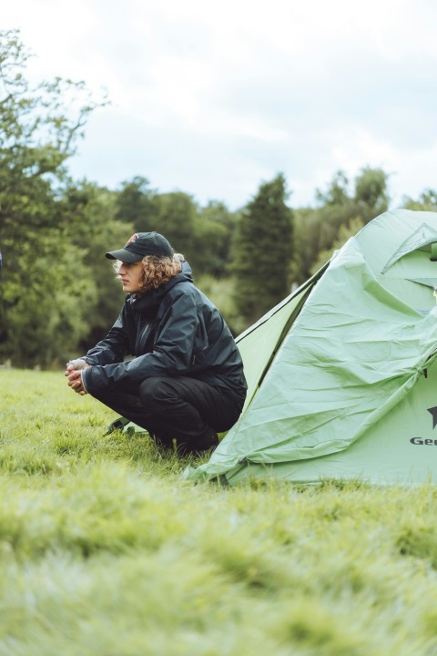 man in black jacket sitting on green tent during daytime mhltOhbe5