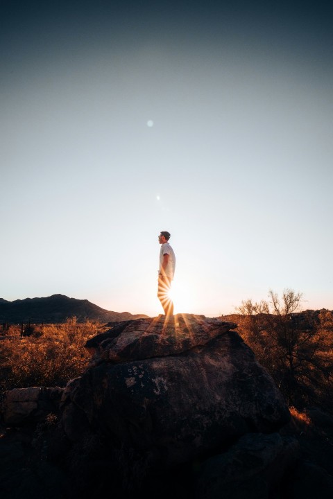 man in white long sleeve shirt standing on brown rock during daytime