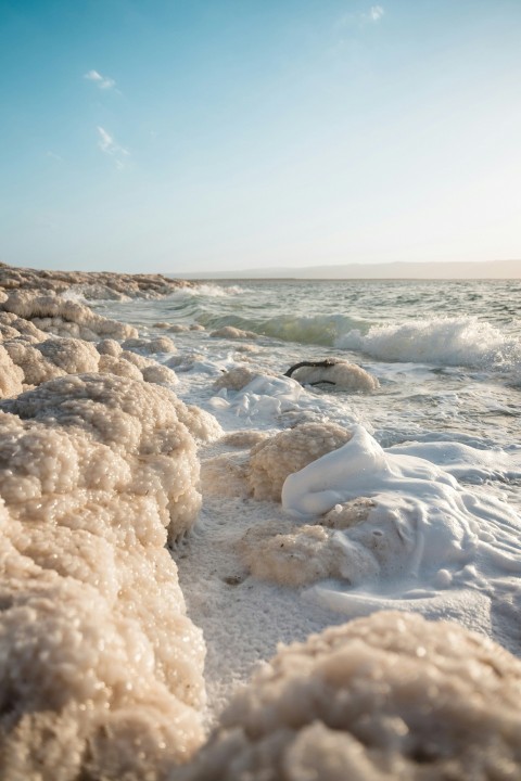 a beach covered in ice and water under a blue sky