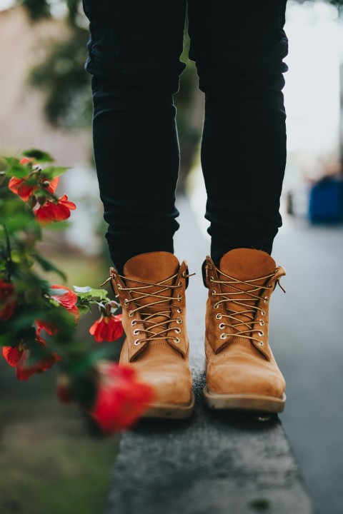 person wearing pair of brown boots near flowers