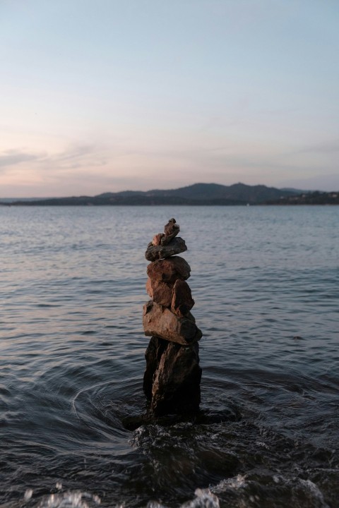 brown rock formation on body of water during daytime