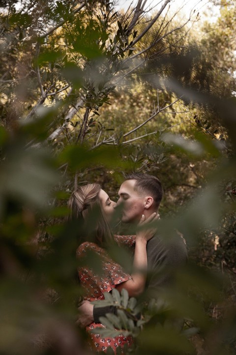 man in green crew neck t shirt kissing woman in red and white floral dress