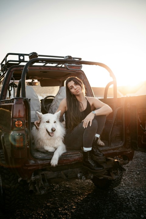 a person sitting in a vehicle with a dog in the passenger seat wLRHQqjwb