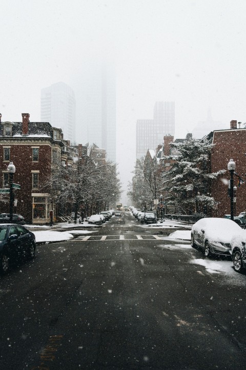 a snowy street with cars parked on the side of it