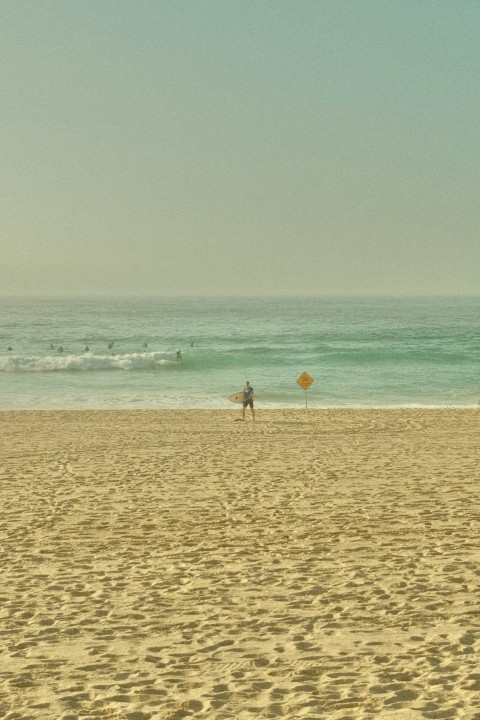 a person standing on a beach with a surfboard