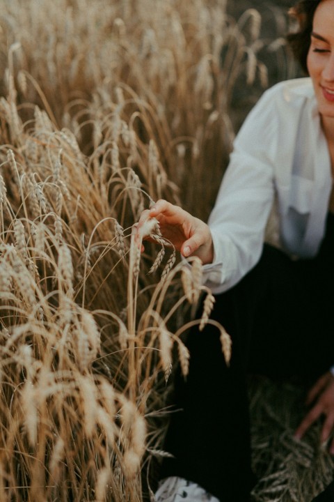 man in white dress shirt and black pants holding brown grass during daytime