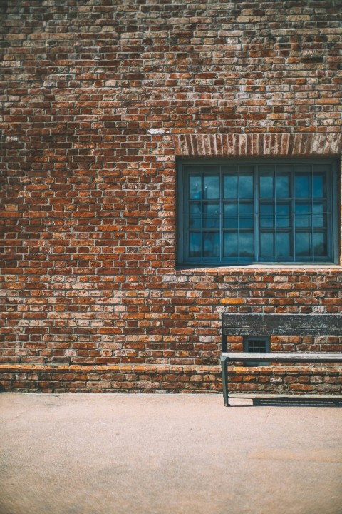 gray bench beside brown brick wall