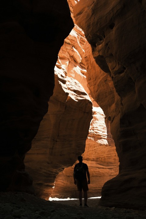 man in black jacket standing on brown rock formation during daytime