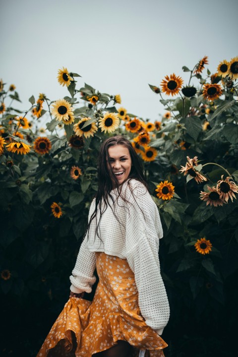 smiling woman standing beside black eyed susan flower field during daytime