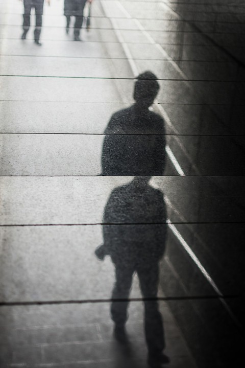 a shadow of a man walking down a sidewalk