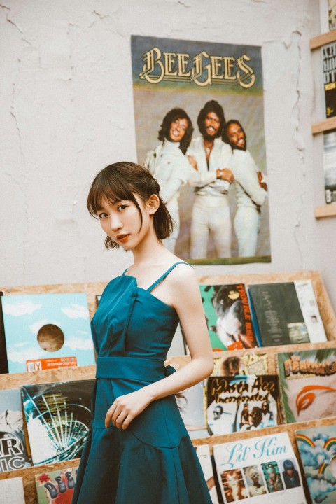 woman in blue tank top standing beside wall with posters