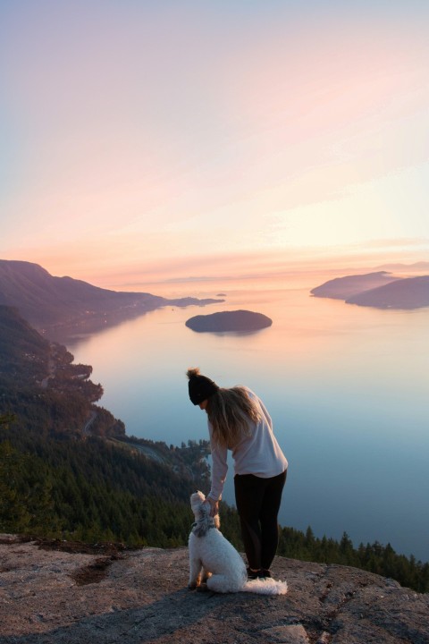 woman standing beside dog near the body of water 3en