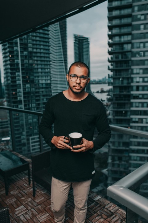 man in black crew neck sweater standing beside glass curtain