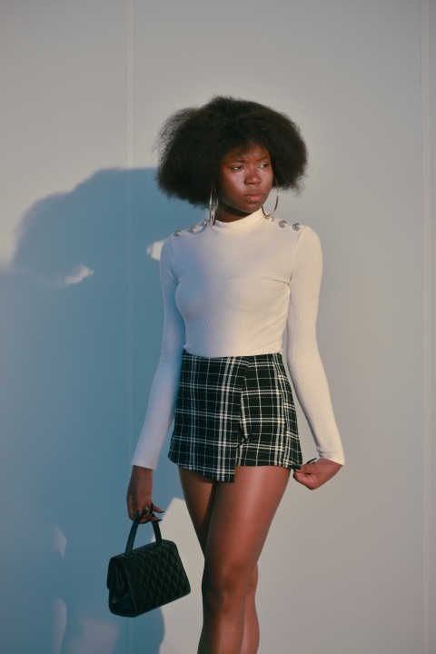 a woman in a white shirt and plaid skirt aQue