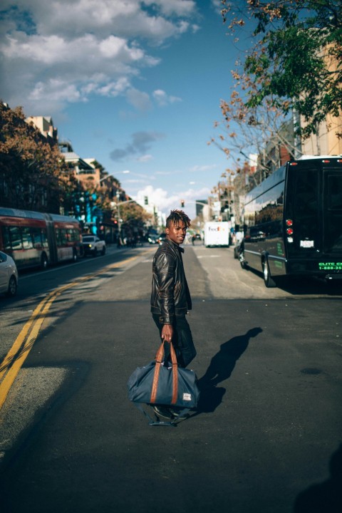 man walking on the street while carrying bag