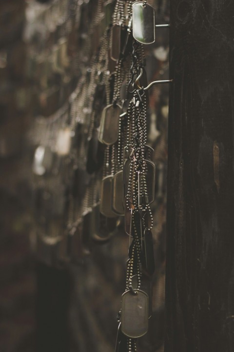 silver colored god tags hanging on hooks shallow focus photography