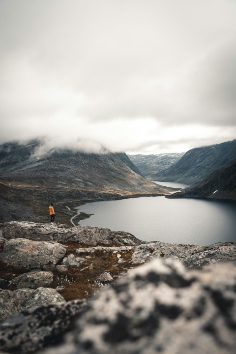 a person standing on top of a mountain next to a lake