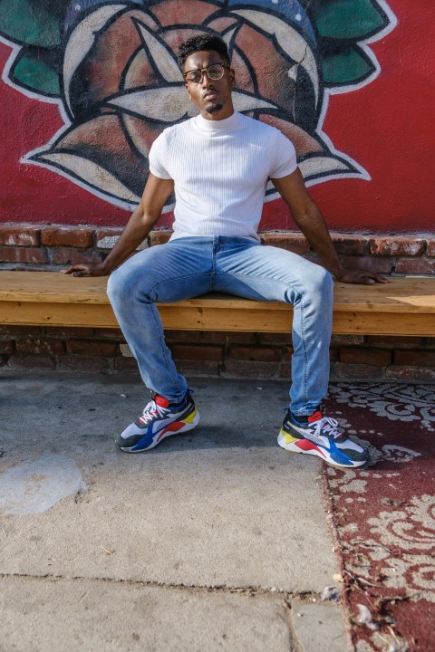 man in white crew neck t shirt and blue denim jeans sitting on brown wooden bench