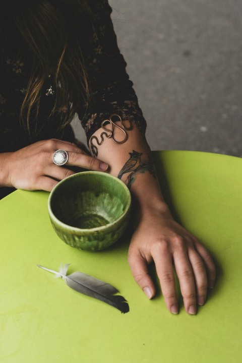 a woman sitting at a table with a green bowl MU6A