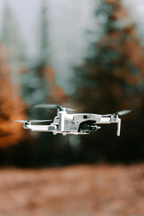 gray drone flying in mid air during daytime