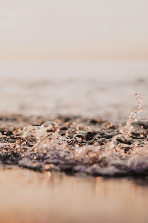 water splash on brown sand during daytime DpiOF