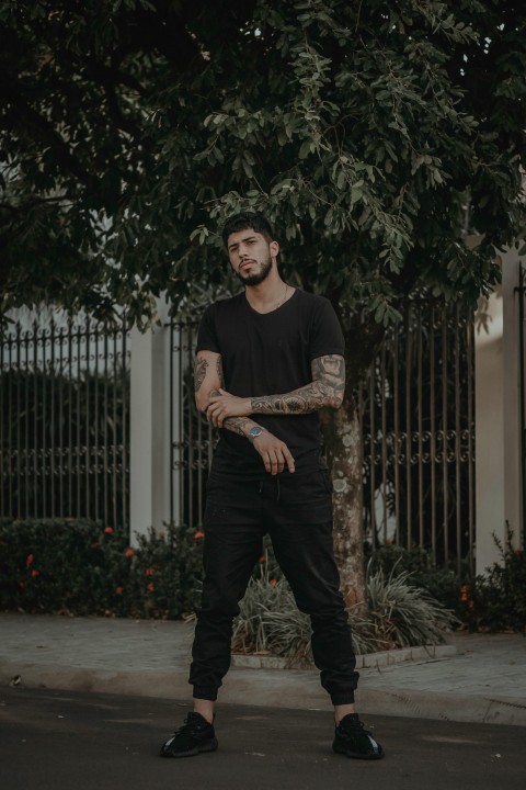 man in black shirt standing on road near fence