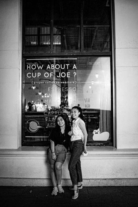 a couple of women sitting next to each other in front of a window