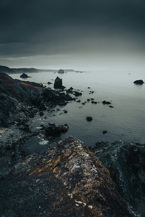 a rocky beach with a body of water in the background