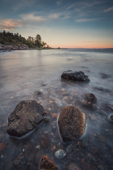 black rock formation on sea shore during sunset