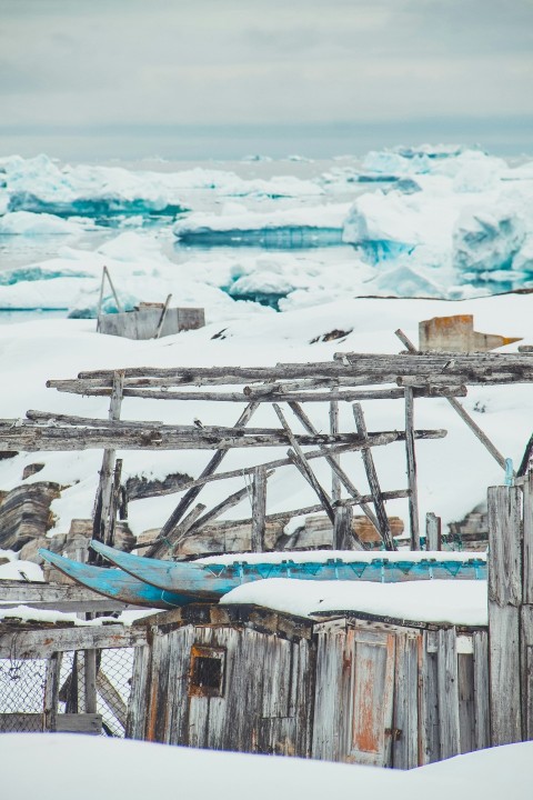 an old wooden structure in the snow with ice behind it