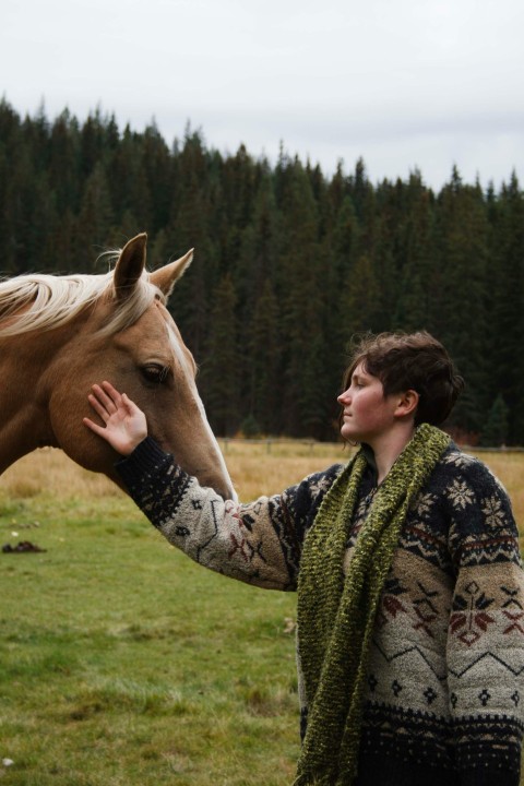 woman in black and green floral long sleeve shirt riding brown horse during daytime 5yB