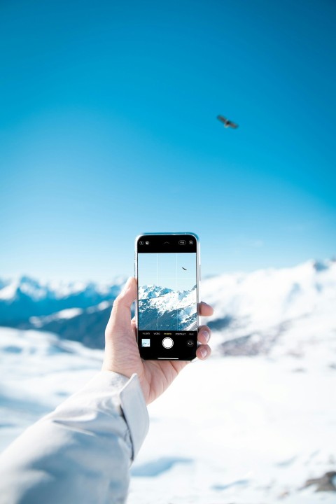 person taking photo of snow covered mountain during daytime