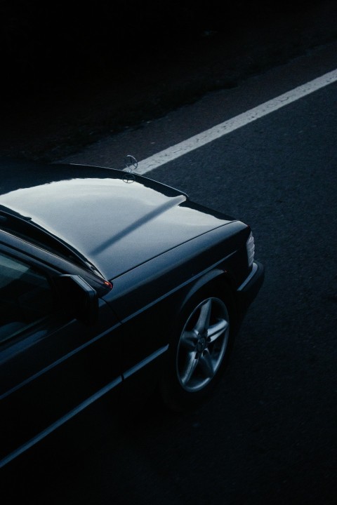 a black car driving down a street at night