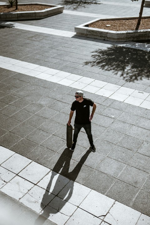 man in black t shirt and black pants standing on gray concrete brick floor during daytime