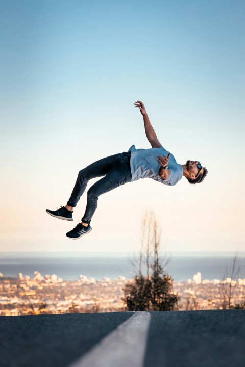 man in blue t shirt and blue denim jeans jumping on air during daytime