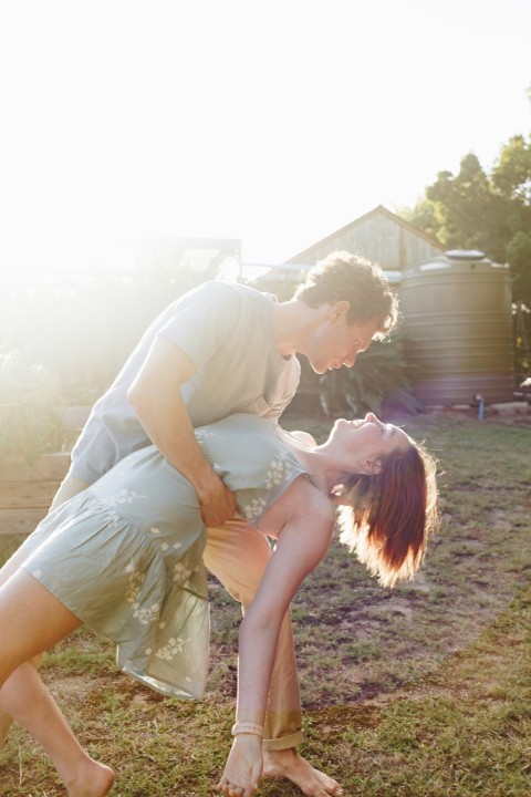 man in green t shirt kissing woman in white dress