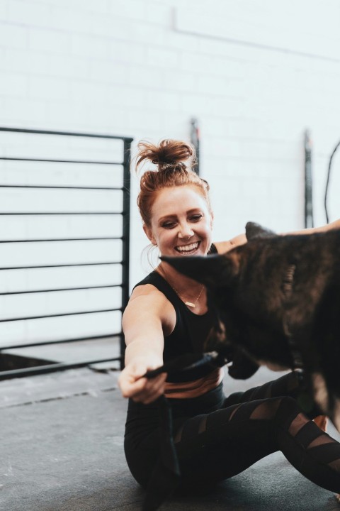 girl in pink t shirt hugging black short coated dog v