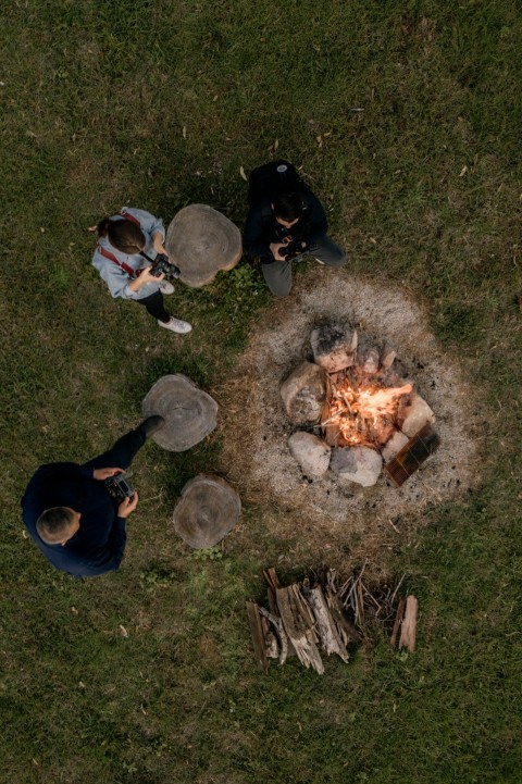 people sitting on grass field near bonfire during daytime W