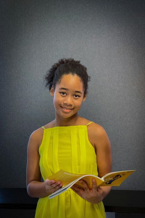 a woman in a yellow dress holding a book ZkBsLZaUd