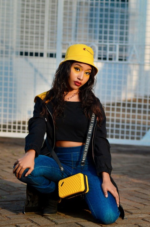 a woman sitting on the ground wearing a yellow hat